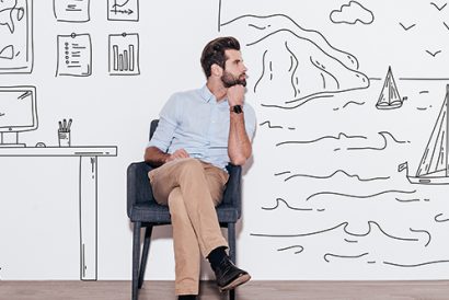 Young handsome man keeping hand on chin and looking away while sitting in the chair against illustration of fjord vs. working place